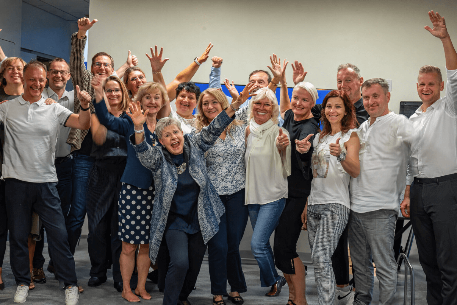 Group of people celebrating with raised hands and joyful expressions.